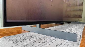 Крупный план ножек и нижней кромки 98-дюймового телевизора TCL 98C7K на дорожке для стола в столовой