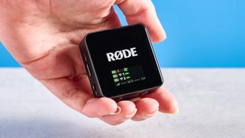 Rode Wireless GO Gen 3 Mikrofon-Set mit einem Empfänger, zwei Sendern und Zubehör wie Fell-Windschutz, Ladeanschlüssen und Kabeln auf blauem Hintergrund