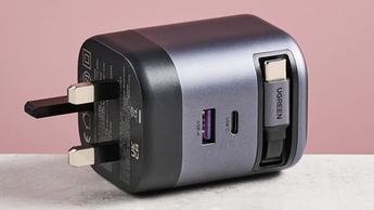 Ugreen Nexode 65W USB-C oplader med indtrækkeligt kabel vist på en lyserød baggrund