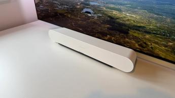 The Sonos Ray soundbar photographed on a white desk in front of a Philips OLED TV