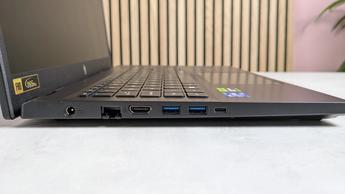 나무 책상 위에 놓인 Acer Nitro V 15 노트북의 왼쪽 포트들, 뒤에는 식물과 분홍색 벽이 보임