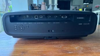 Проектор Epson EH-QB1000 для домашнего кинотеатра на деревянном столе, вид сзади: элементы управления и HDMI-порты