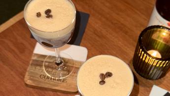 Um copo de coquetel espresso martini sobre uma mesa de bar