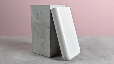 Banco de batería portátil Samsung de 45W y 20.000 mAh apoyado en un pedestal sobre un escritorio con fondo rosa