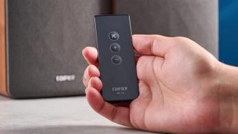 Die Edifier R1280T Regallautsprecher im Holzfurnier vor blauem Hintergrund, mit Fokus auf die Lautstärkeregler, die Lautsprechertreiber, den Hochtöner, die RCA- und AUX-Eingänge sowie die Fernbedienung