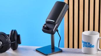Das NZXT Capsule Elite Gaming-Mikrofon in Schwarz mit Nierenkondensator-Design, vor blauem Hintergrund gezeigt, mit zwei Bedienelementen und RGB-LED-Panels
