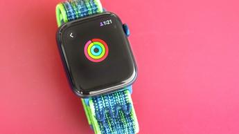 Apple Watch SE sobre una mesa roja mostrando los Anillos de Actividad casi completos