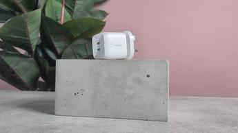 Belkin BoostCharge Pro GaN Dual vægoplader 45W vist på en blok med lyserød baggrund og en grøn plante