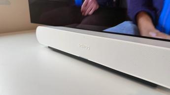 The Sonos Ray soundbar photographed on a white desk in front of a Philips OLED TV