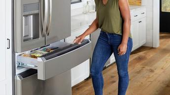 Mujer abriendo el cajón del congelador de un refrigerador Frigidaire GRMC2273BF de 610 litros, cuatro puertas tipo francés, con profundidad de mostrador