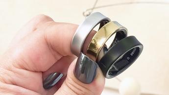 Drei Samsung Galaxy Ring Smart-Ringe in Silber, Gold und Schwarz werden in einer Hand gehalten