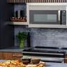 Microondas de convección GE Profile instalado sobre la estufa en una cocina moderna de color gris oscuro