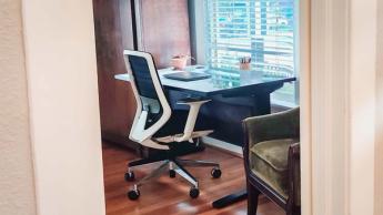 Un escritorio elevable Uplift V2 acompañado de una silla ergonómica Branch