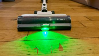 Aspiradora inalámbrica tipo escoba Tineco Pure One A50S con cabezal iluminado detectando polvo en piso de madera