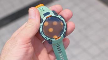 Primer plano del smartwatch Garmin Instinct 3 con GPS en color Twilight neotrópico, con caja gris y naranja y correa verde espuma marina