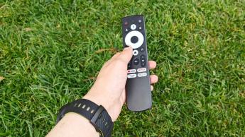 Пульт портативного ультракороткофокусного проектора Optoma Photon Go в руке на зеленой траве