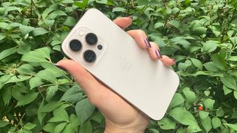 Person som håller iPhone 16 Pro i ökenfärgad titan
