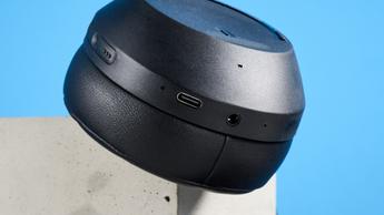 Schwarze Mixx StreamQ C4 Kopfhörer mit weichen Ohrpolstern und Tasten auf blauem Hintergrund