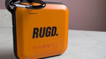 Cargador portátil RUGD Power Brick sobre un escritorio con fondo rosa