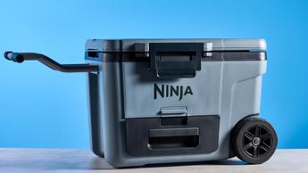 Nevera con ruedas Ninja FrostVault 45QT mostrada contra un fondo azul, destacando su diseño portátil y construcción resistente.