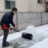 Personne déblayant la neige de la terrasse avec un accessoire professionnel