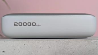 Vista lateral del banco de energía Aukey Spark Mini 20000 expuesto con una pared rosa y una planta en maceta al fondo
