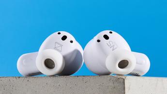 Ein Paar weiße AKG N5 Hybrid-Ohrhörer von Harman, präsentiert in ihrer Ladehülle mit enthaltenem Zubehör