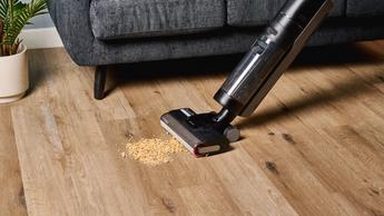 Aspiradora seca y húmeda Dreame H12 Pro recogiendo cereal de un piso de madera