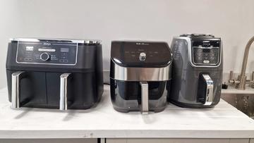 Três fritadeiras elétricas lado a lado em uma bancada de cozinha