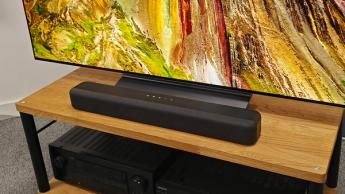 Саундбар Amazon Fire TV, установленный на деревянной тумбе перед телевизором