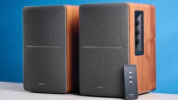 Edifier r1280t Regallautsprecher in Holzoptik Braun mit sichtbaren Lautstärkereglern, Treibern, Hochtönern, RCA- und AUX-Eingängen sowie Fernbedienung vor blauem Hintergrund