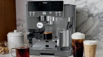 Il Ninja Luxe Cafe in grigio antracite con bevande disposte intorno, che mostra un'atmosfera moderna da caffetteria.