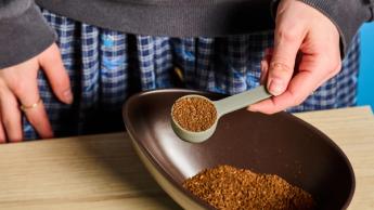 Cafeteira pour-over Wacaco Cuppamoka de aço inoxidável com filtros de papel marrom e tampa em formato de copo em fundo azul