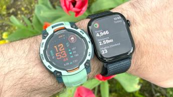 Nahaufnahme einer türkisen Garmin Instinct 3 und einer schwarzen Apple Watch Series 10 mit blauem Armband am Handgelenk einer Person