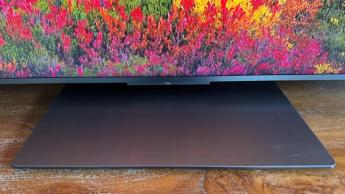 Крупный план ЖК-телевизора TCL 65C8K на подставке, на экране — яркие цветы