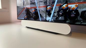 The Sonos Ray soundbar photographed on a white desk in front of a Philips OLED TV