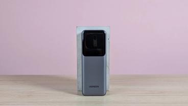 Batería externa Ugreen Nexode 20.000mAh 165W sobre un escritorio con fondo rosa