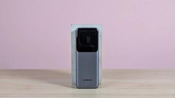 Ugreen Nexode Power Bank 20.000 mAh 165W hviler på en sokkel på et skrivebord med lyserød baggrund