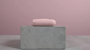 Sideprofil af VRURC T6S bærbar powerbank vist på et skrivebord med lyserød baggrund