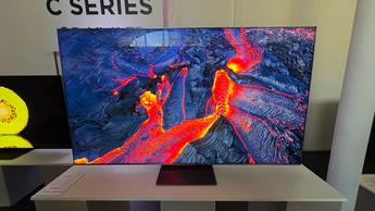 Телевизор TCL C8K на белой тумбе, отображающий яркие природные пейзажи