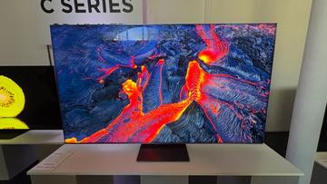 Телевизор TCL C8K на белой тумбе, отображающий яркие природные пейзажи