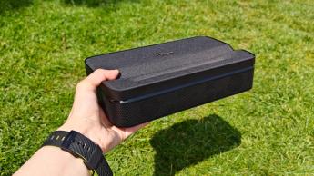 Портативный ультракороткофокусный проектор Optoma Photon Go в руке над зеленой лужайкой