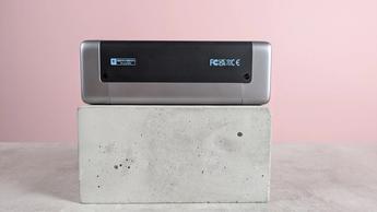 Cuktech 20 powerbank set fra siden på en sokkel på et skrivebord med lyserød baggrund