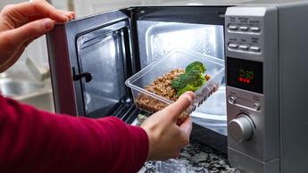 Un recipiente de plástico para alimentos siendo colocado en un microondas