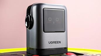 Cargador UGreen Uno de 100 W conectado a la corriente, mostrando un emoji sonrojado en la pantalla