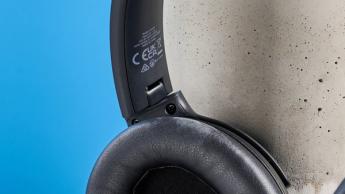 Schwarze kabellose Earfun Tune Pro Kopfhörer mit weichen, grauen Kunstleder-Ohrpolstern vor blauem Hintergrund