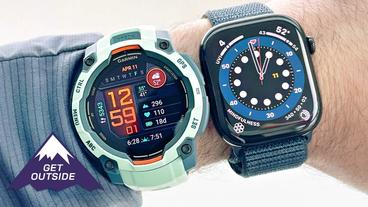 Nahaufnahme eines Handgelenks mit einer türkisfarbenen Garmin Instinct 3 und einer Apple Watch Series 10 mit blauem Armband