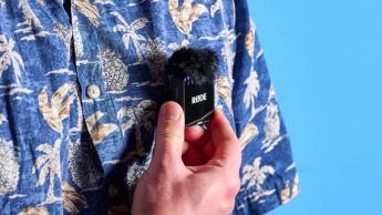 Das Rode Wireless GO Gen 3 Mikrofon-Set mit einem Empfänger, zwei Sendern und Zubehör wie Fell-Windschutz, Ladeanschlüssen und Kabeln auf blauem Hintergrund