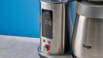La macchina da caffè Breville Luxe con caraffa termica in metallo argentato, cestello portafiltro, serbatoio dell'acqua rimovibile e una selezione di cestelli portafiltro e filtri di carta mostrati accanto a una manopola di controllo dell’erogazione