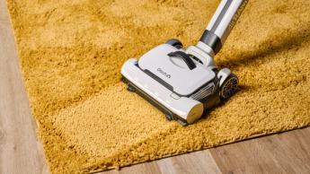Foto de la aspiradora Gtech AirRam 3 quitando suciedad de una alfombra gruesa amarilla